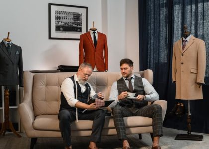Two tailors in a stylish workshop discussing custom suit designs surrounded by elegant suits.