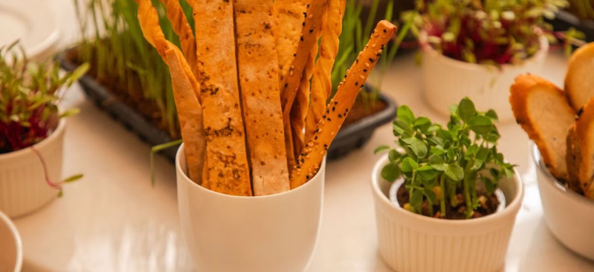 Aesthetic presentation of artisan breadsticks and fresh microgreens in elegant white cups.