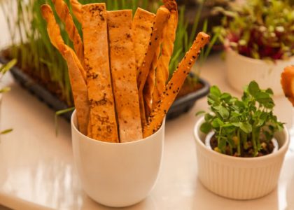 Aesthetic presentation of artisan breadsticks and fresh microgreens in elegant white cups.
